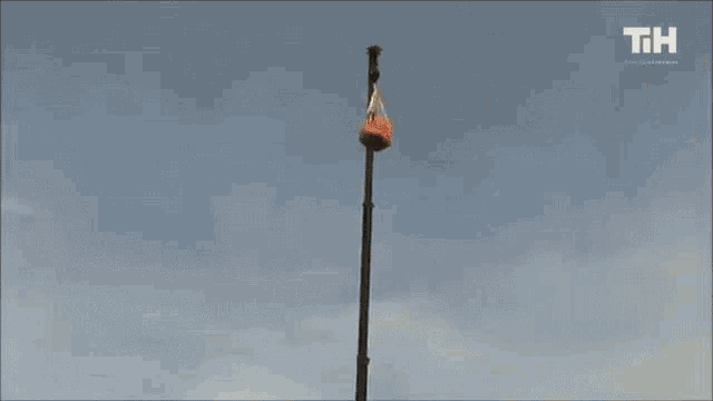 a large orange balloon is being lifted by a crane with the letters th visible in the background
