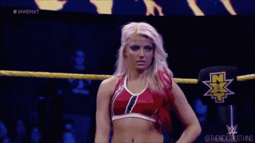 a woman is standing in a wrestling ring wearing a red and white top .