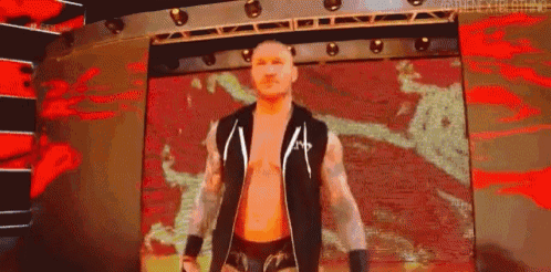 a wrestler is standing on a stage in front of a red and black background .
