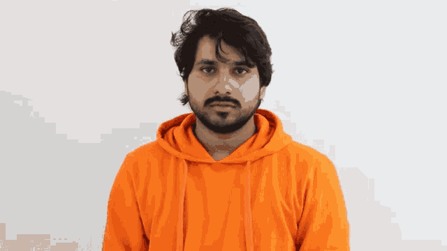a man with a beard is wearing a bright orange hoodie