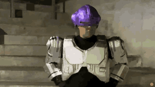 a man wearing a purple helmet and armor with the letter t on his chest