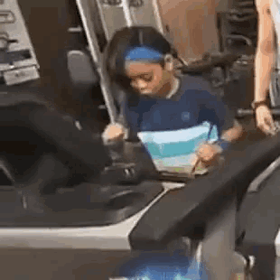 a little girl is standing on a treadmill in a gym .