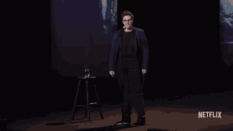 a man stands on a stage in front of a microphone with a netflix logo in the corner
