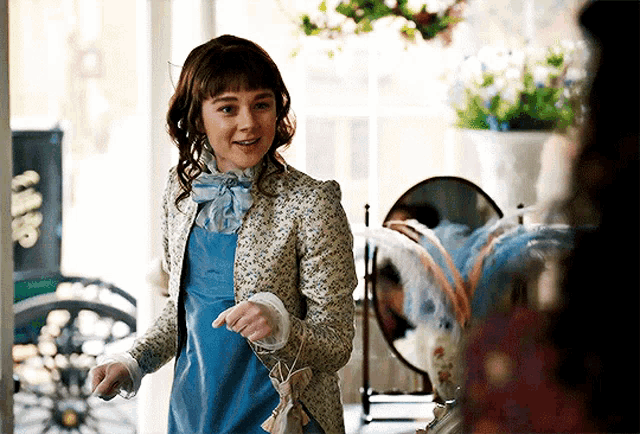 a woman wearing a blue dress and a floral jacket is smiling