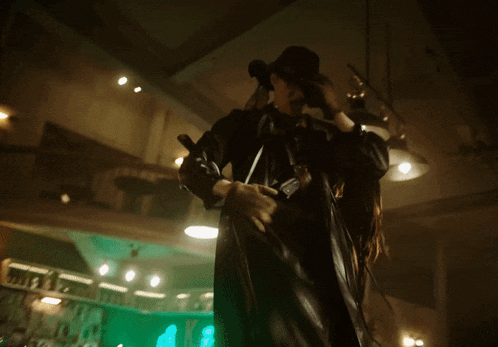 a man in a cowboy hat holds a gun in a dark room