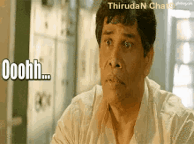 a man with a surprised look on his face is sitting at a table with the words ooohh written on his face .