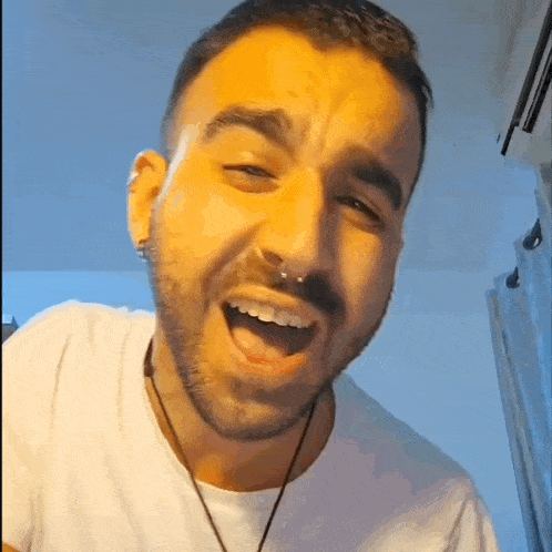 a man with a beard is making a funny face while wearing a nose ring .