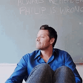 a man in a blue shirt is sitting in front of a chalkboard that says always remember philip is wrong