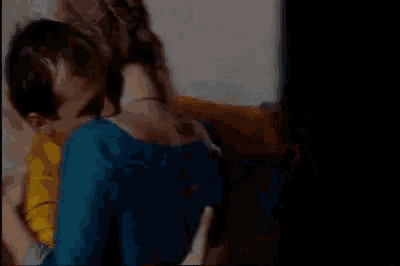 a man and a woman are hugging each other in a room . the woman is wearing a yellow jacket .