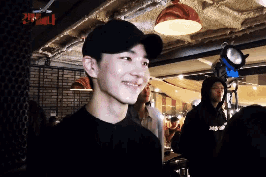 a man wearing a black hat is smiling in front of a sign that says seoul
