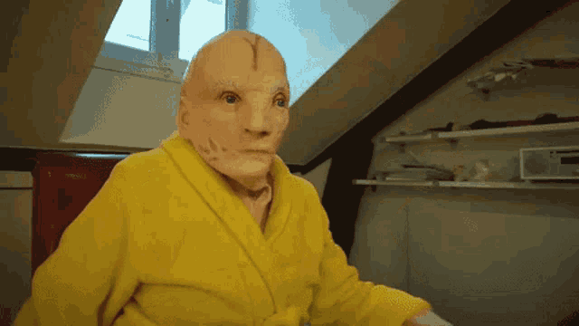 a man wearing a yellow robe has a mask on his head