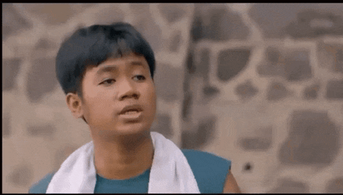a young boy wearing a towel around his neck is making a funny face .