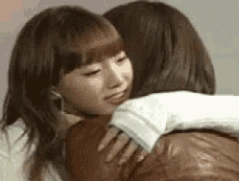 two women are hugging each other and one of them is kissing the other .