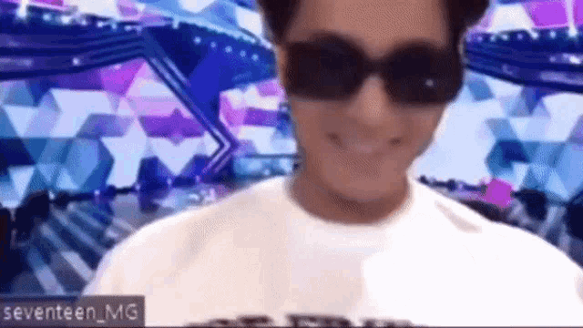 a man wearing sunglasses is smiling in front of a colorful background .