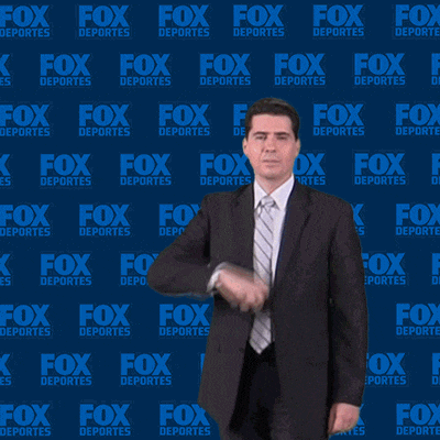 a man in a suit stands in front of a fox deportes background