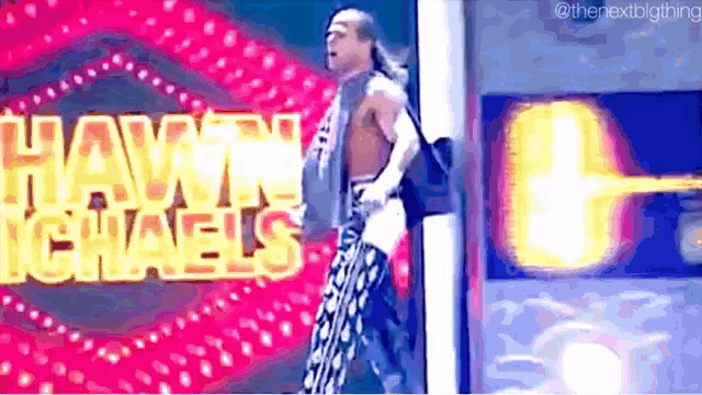 a wrestler is walking in front of a sign that says hawk isaacs