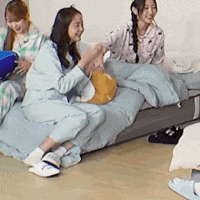 a group of women are sitting on a bed with pillows .