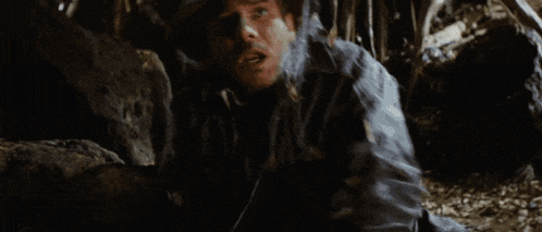 a silhouette of a man holding a sword in a dark room with the sun shining through the window .