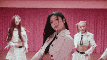 a group of girls are dancing on a stage with pink curtains