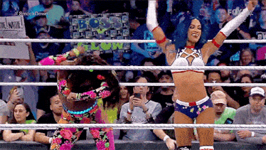 a woman in a wrestling ring with her arms in the air
