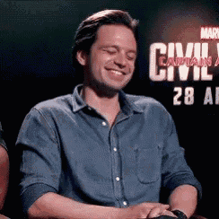 a man in a denim shirt is sitting in front of a sign that says civil war .