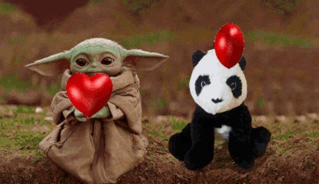 a baby yoda holding a red heart next to a panda bear
