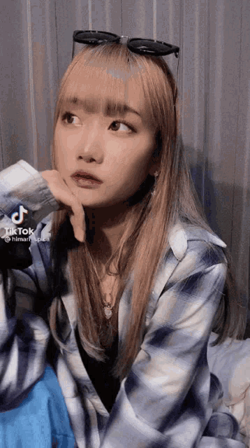 a woman wearing sunglasses and a plaid shirt has a tiktok account .