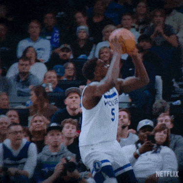 a man in a white jersey with the number 5 on it is holding a basketball