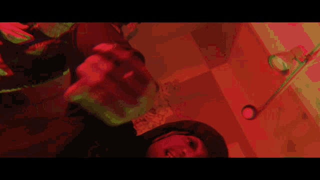 a person in a hooded jacket is standing in a dark room with red lights