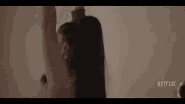 a woman with long hair is standing in front of a white wall with her arms outstretched .