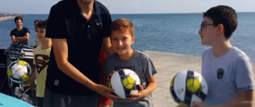 a boy wearing a superman shirt holds a soccer ball