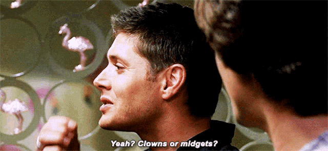 two men are standing next to each other and one of them is asking the other if he is a clown or midget .