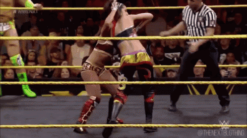 two women are wrestling in a wrestling ring with a referee watching .