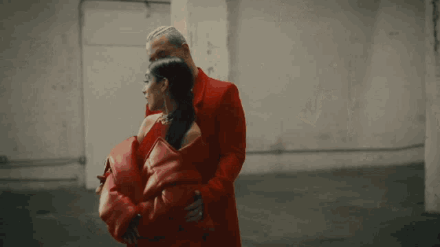 a man in a red suit is hugging a woman in a red dress .