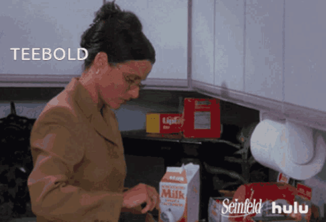 a woman in a kitchen with a carton of milk and the word teebold behind her