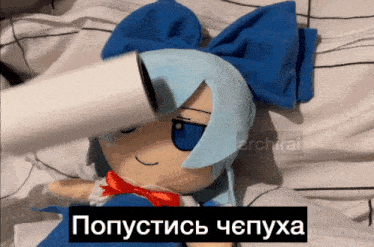 a stuffed doll with blue hair and a red bow is laying on a bed with a caption in russian