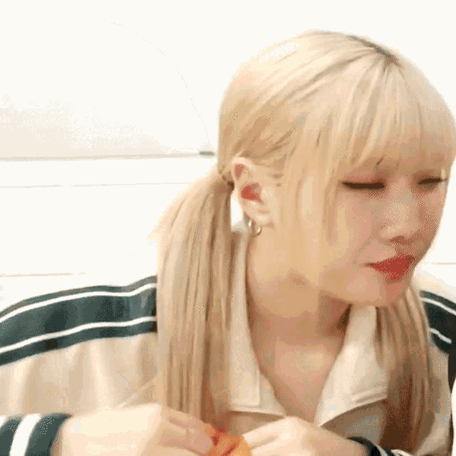 a woman with blonde hair and pigtails is wearing a green and white jacket and red lipstick .