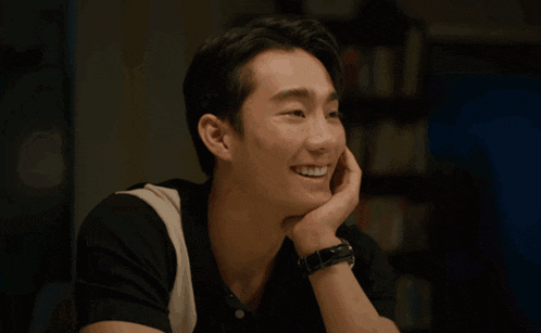 a man with a watch on his wrist smiles with his hand on his face