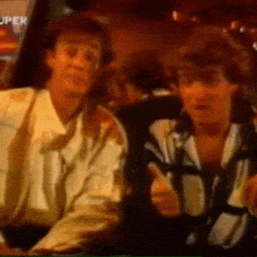 two men are sitting in a car giving a thumbs up .