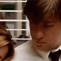 a man and a woman are sitting next to each other in front of a window with blinds .