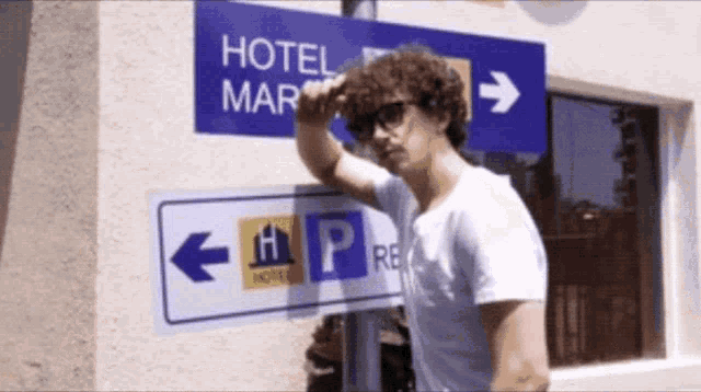 a man is standing in front of a hotel mar sign