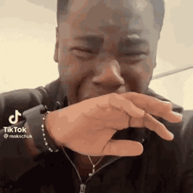 a man is crying while covering his face with his hand .