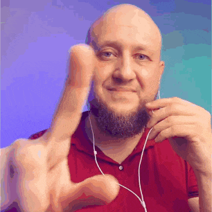 a bald man with a beard is wearing earphones and giving a thumbs up sign .