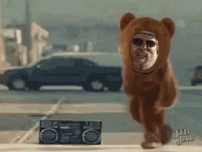 a man in a teddy bear costume is running in front of a boombox with jub jab written on it