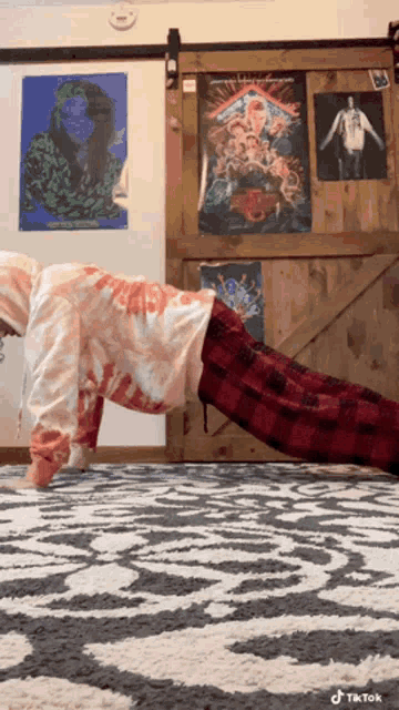 a person doing push ups in front of a sliding barn door with posters on the wall