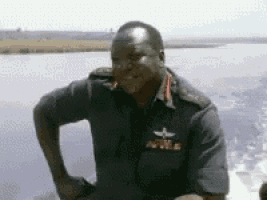a man in a military uniform is standing in front of a body of water ..
