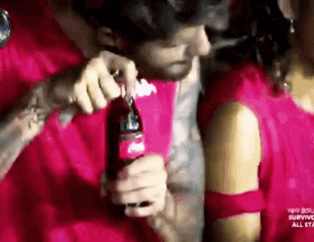 a man is opening a coca cola bottle next to a woman in a red dress