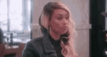 a woman in a black leather jacket is sitting at a table .