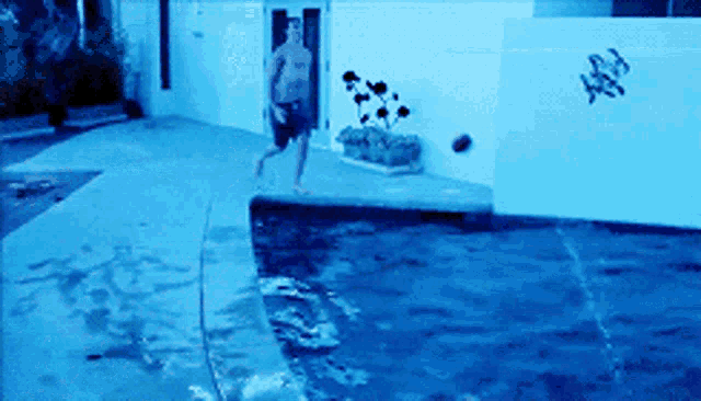 a shirtless man is running towards a swimming pool with a ball in his hand