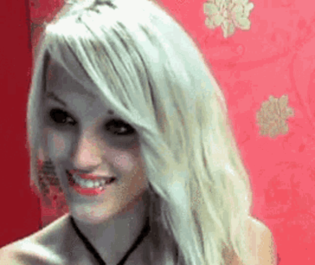 a woman with white hair is smiling in front of a pink wall